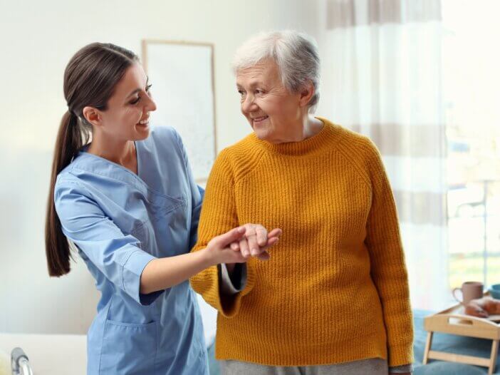 a nurse with a parkinson's patient holding hands and walking