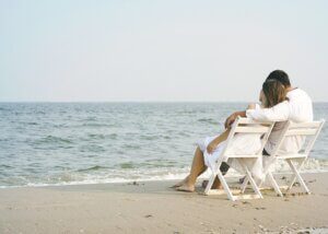 a couple hugging on the beach sitting in lounge chairs