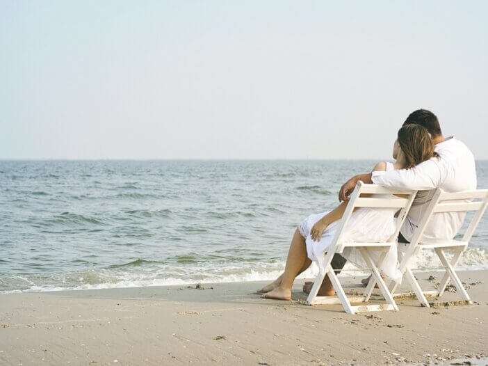 a couple hugging on the beach sitting in lounge chairs