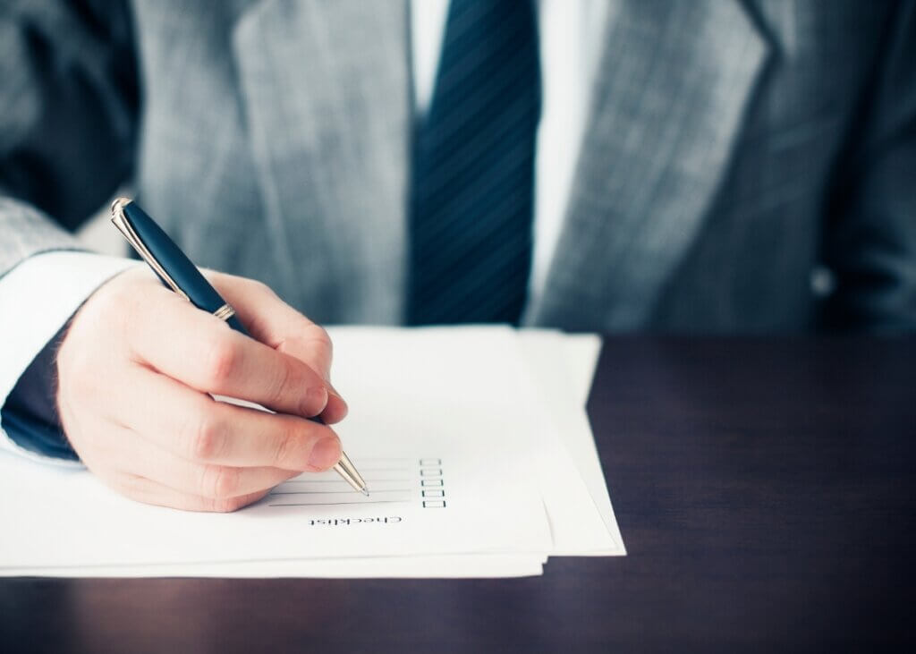 a checklist on the table and a mans hand checking off the boxes.