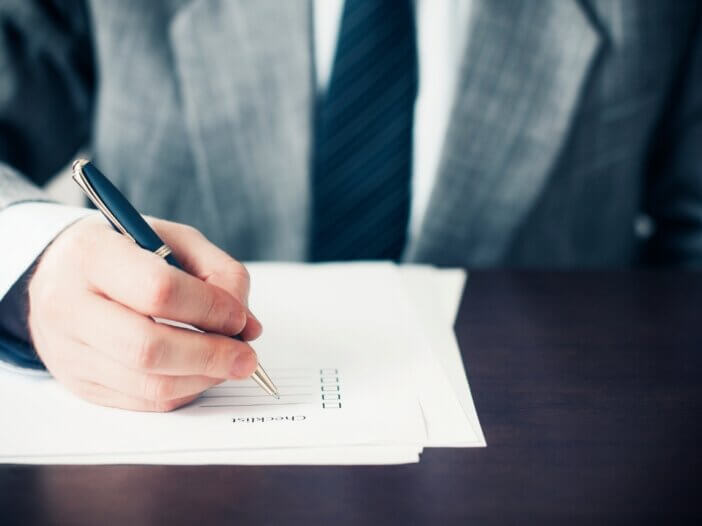 a checklist on the table and a mans hand checking off the boxes.