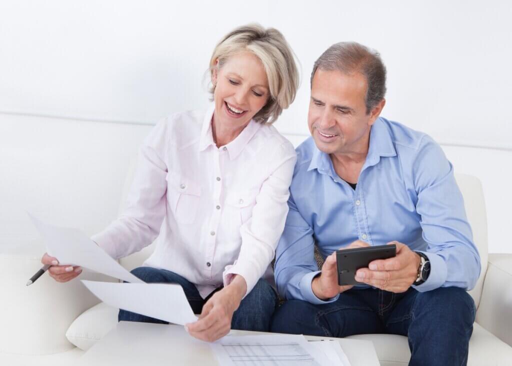 a married couple sitting on the couch looking at documents together