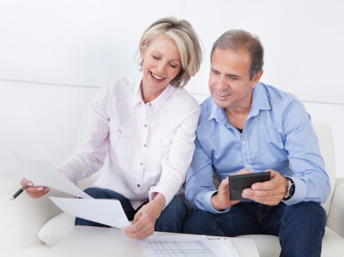 a married couple sitting on the couch looking at documents together