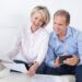 a married couple sitting on the couch looking at documents together