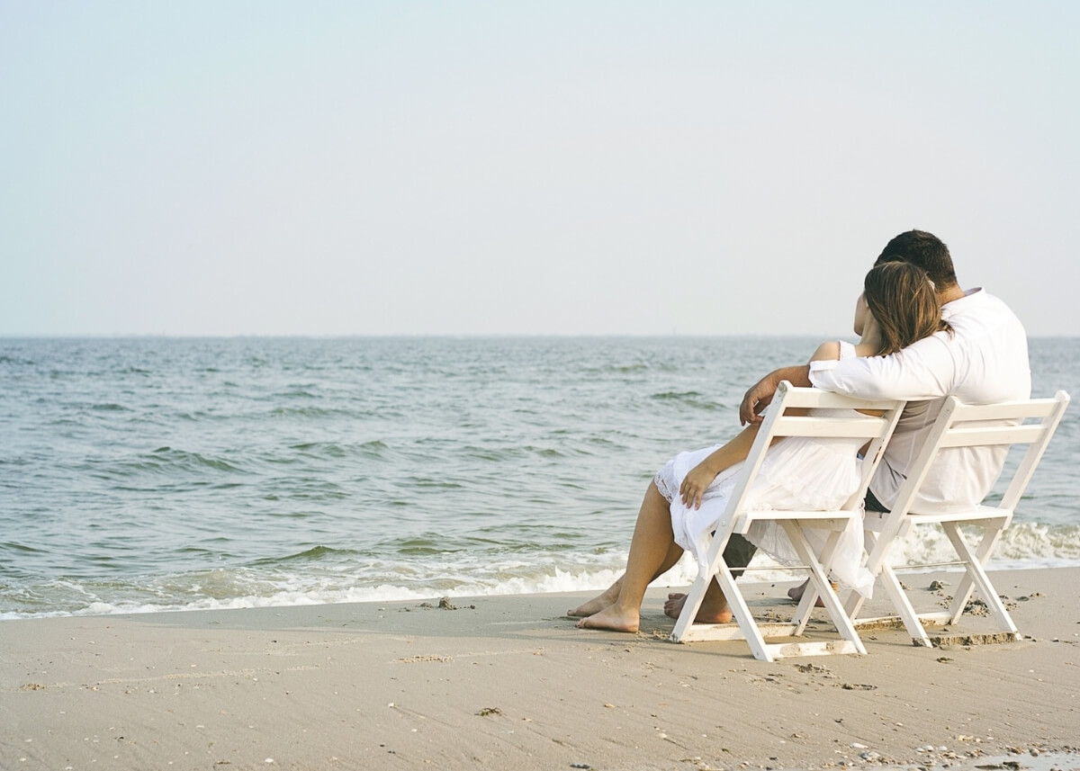 a couple hugging on the beach sitting in lounge chairs
