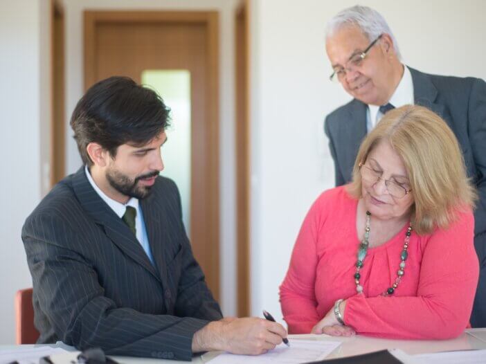 an older couple planning with their lawyer signing papers