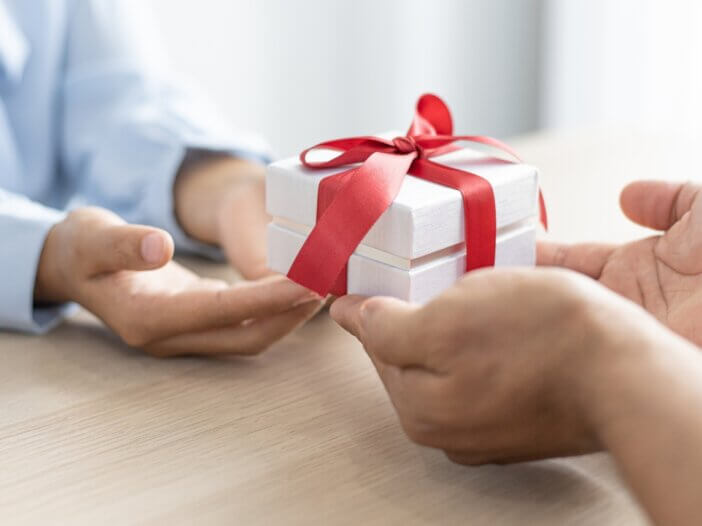 a person holding a gift and giving it to someone