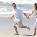 a couple holding hands and running on the beach.