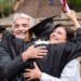 a kid hugging his parents in his graduation cap and gown with his diploma in the air