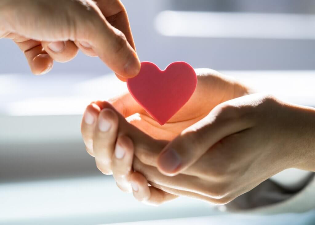 two sets of hands and one is giving a heart shaped figure to the other set of hands