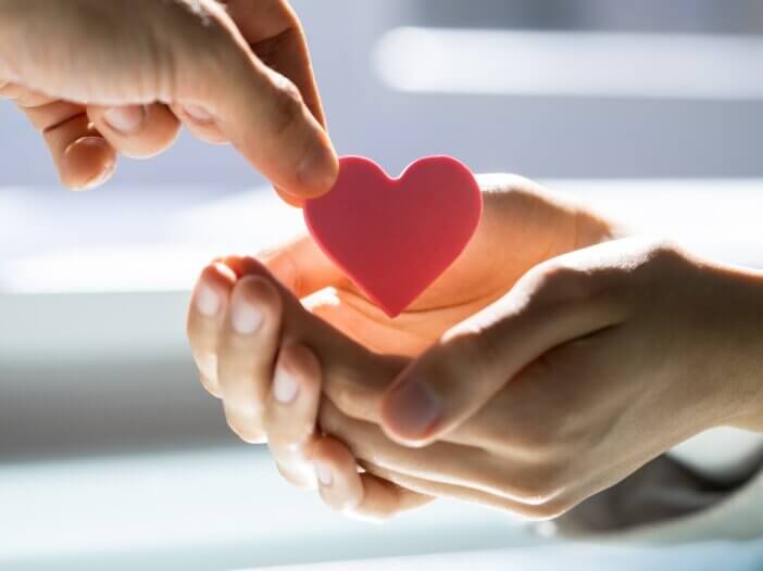 two sets of hands and one is giving a heart shaped figure to the other set of hands