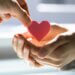 two sets of hands and one is giving a heart shaped figure to the other set of hands