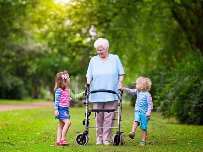 a grandmother walking on her walker with her grandkids on each side of her
