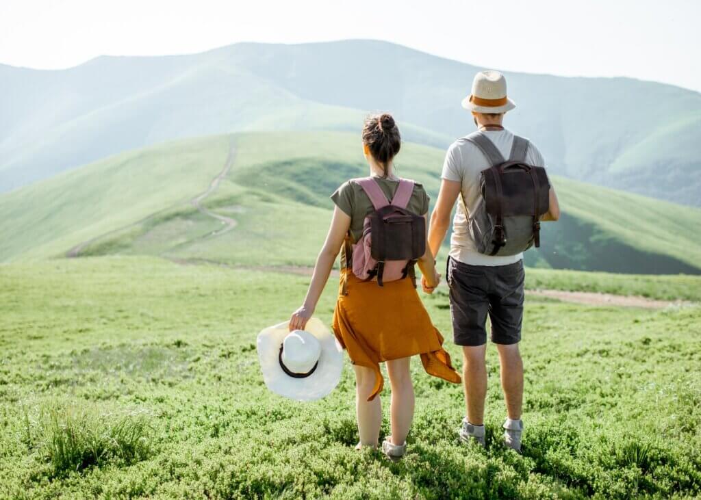 a couple traveling. they are on a mountain holding hands.