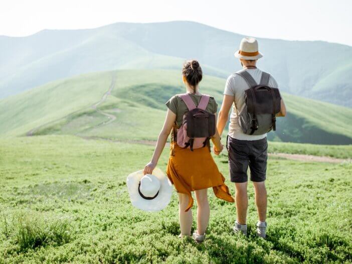 a couple traveling. they are on a mountain holding hands.
