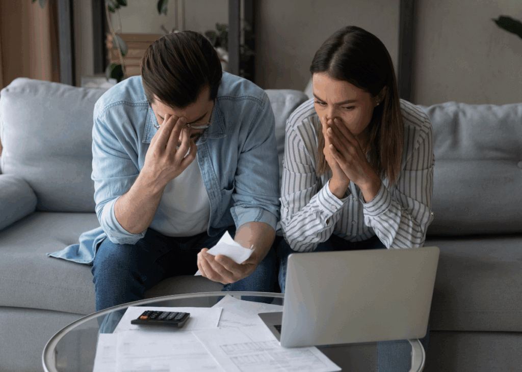 Two spouses looking at financial paperwork in distress.