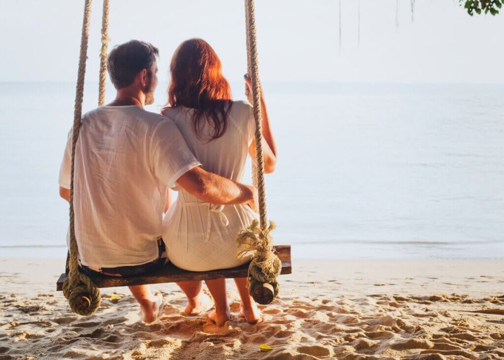 a couple on a swing and a picture of them from behind on a beach on vacation.
