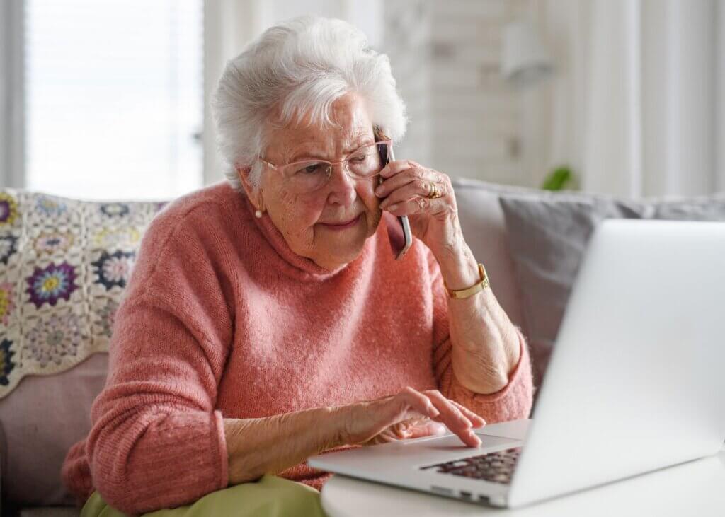 senior in distress checking her computer while on the phone.