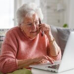 senior in distress checking her computer while on the phone.