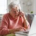 senior in distress checking her computer while on the phone.