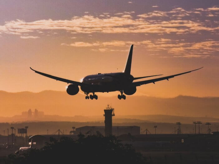 a plane landing from takeoff into the sunset