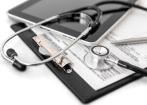 a healthcare clipboard with a patients files and a stethoscope on top