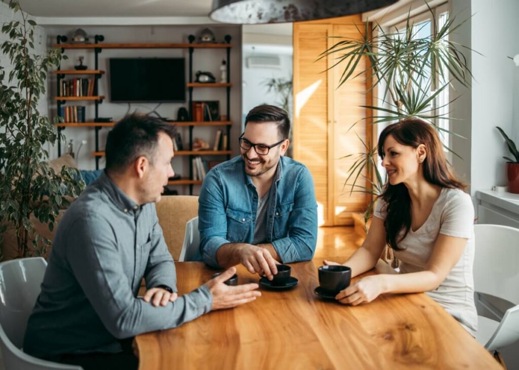 three people sitting at a table discussing something professional. a couple talking to their trustee