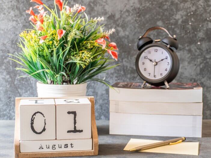 a calendar of august 1st with a plant and a clock
