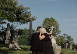 a couple in the cemetery mourning the loss of their loved one.