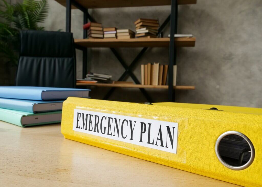 a photo of an emergency binder on a desk titled emergency plan