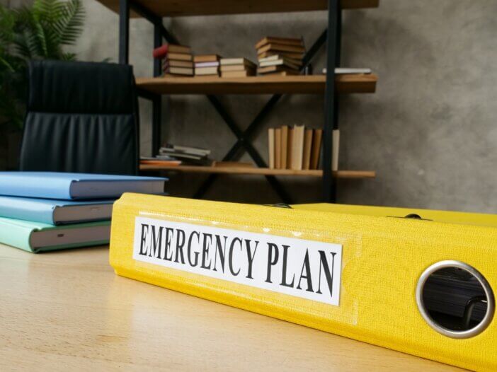 a photo of an emergency binder on a desk titled emergency plan