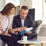 two people sitting down looking at papers together