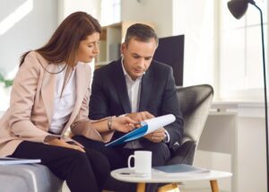 two people sitting down looking at papers together