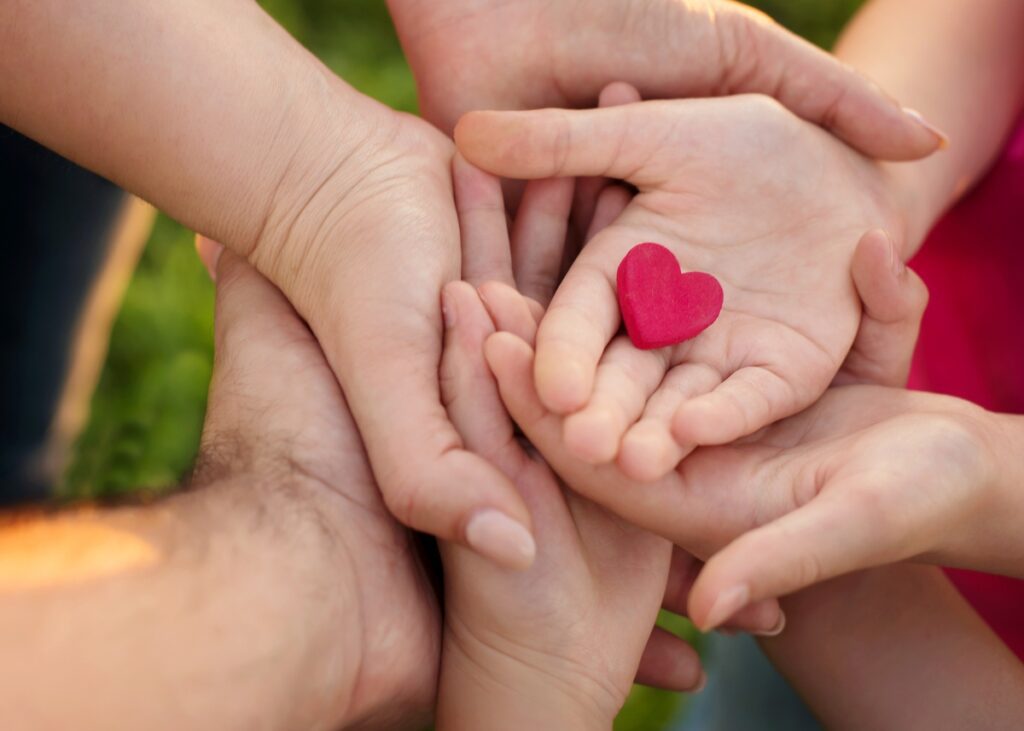 a crowd on hands from all different generations and a heart in the middle