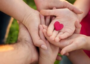 a crowd on hands from all different generations and a heart in the middle