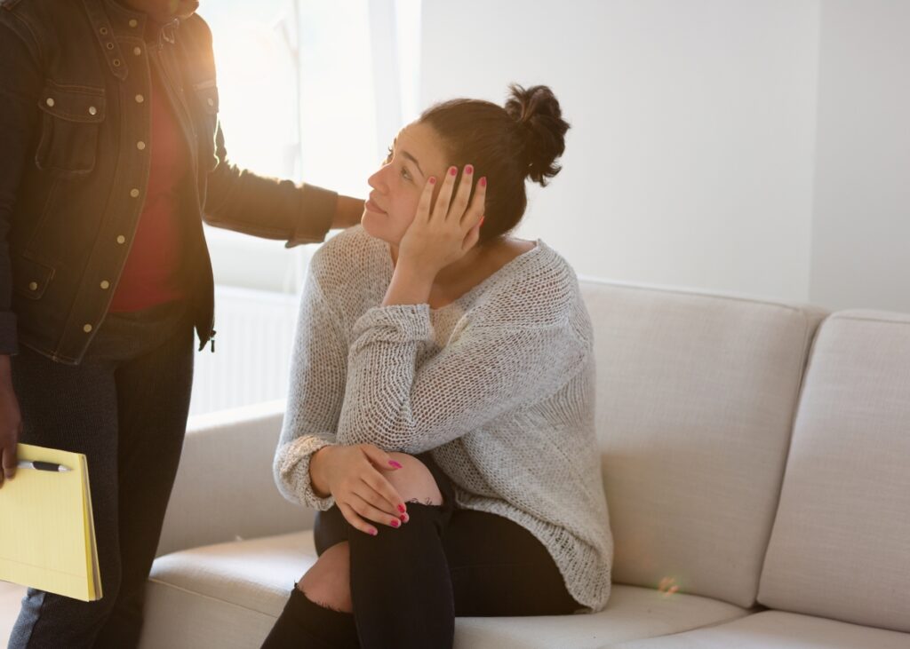 a person on a couch seeming disappointed and sad and then a professional consoling her