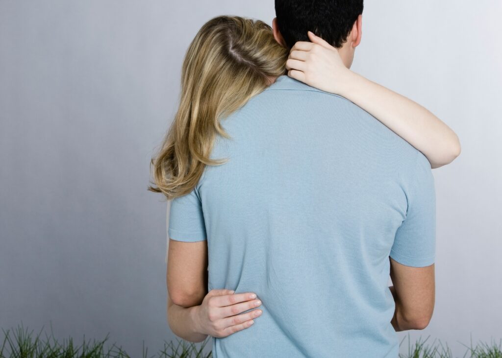 a woman hugging a man and showing it from the back