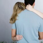 a woman hugging a man and showing it from the back