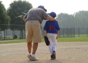 a dad walking with his kid after a baseball game