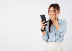 a woman looking at her phone looking shocked at sticker shock