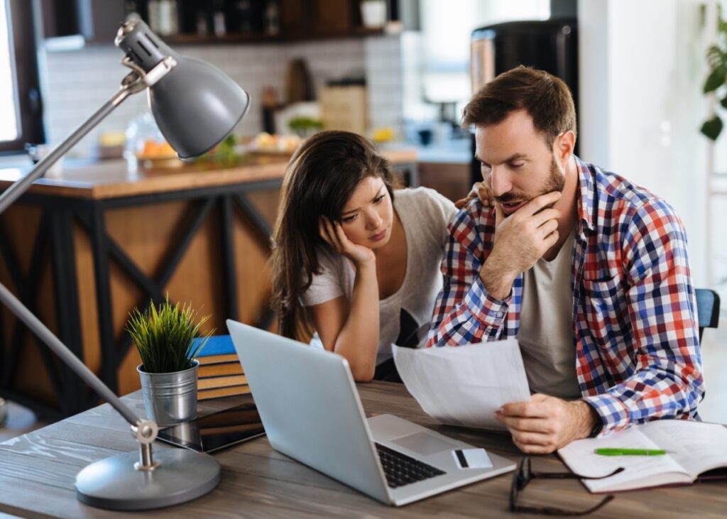 a couple with sticker shock looking at their computer and the cost