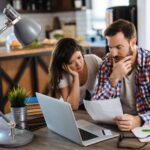 a couple with sticker shock looking at their computer and the cost