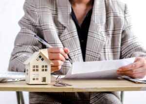 a person reviewing business documents and then there is a model of a house in front of them on their desk