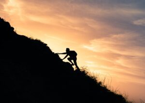a person climbing up a mountain at sunset