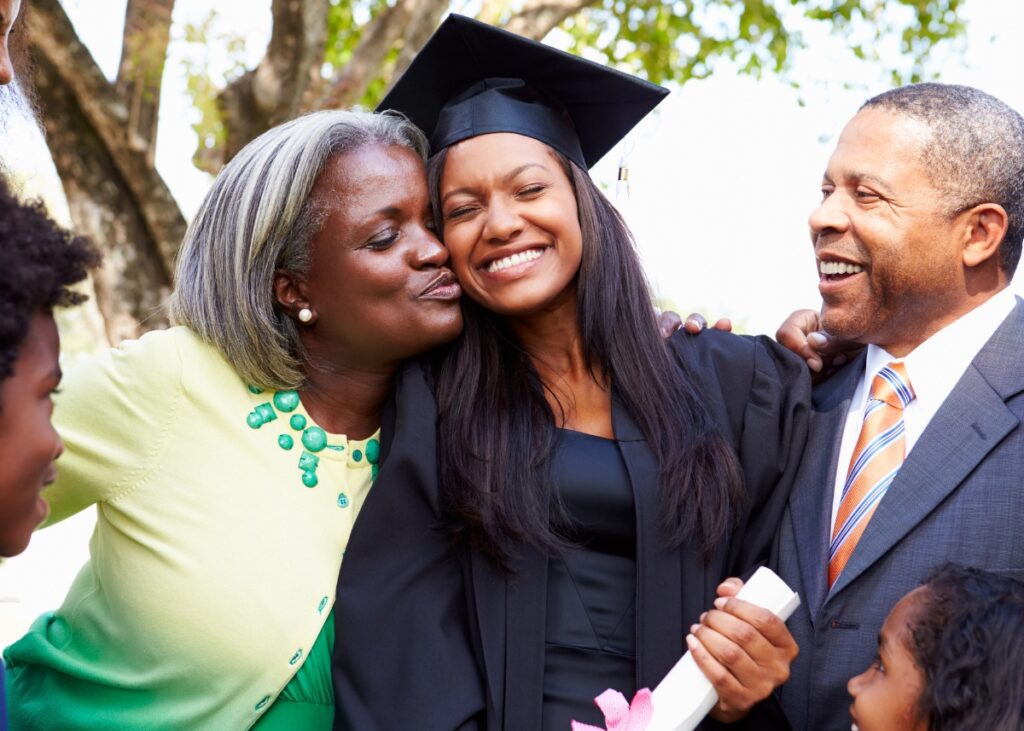 a young adult hugging their parents at graduation