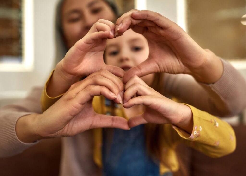 a mom and a child doing heart hands showing their gratitude for each other