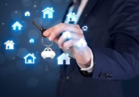 Businessman in suit holding keys with house graphics around and dark background