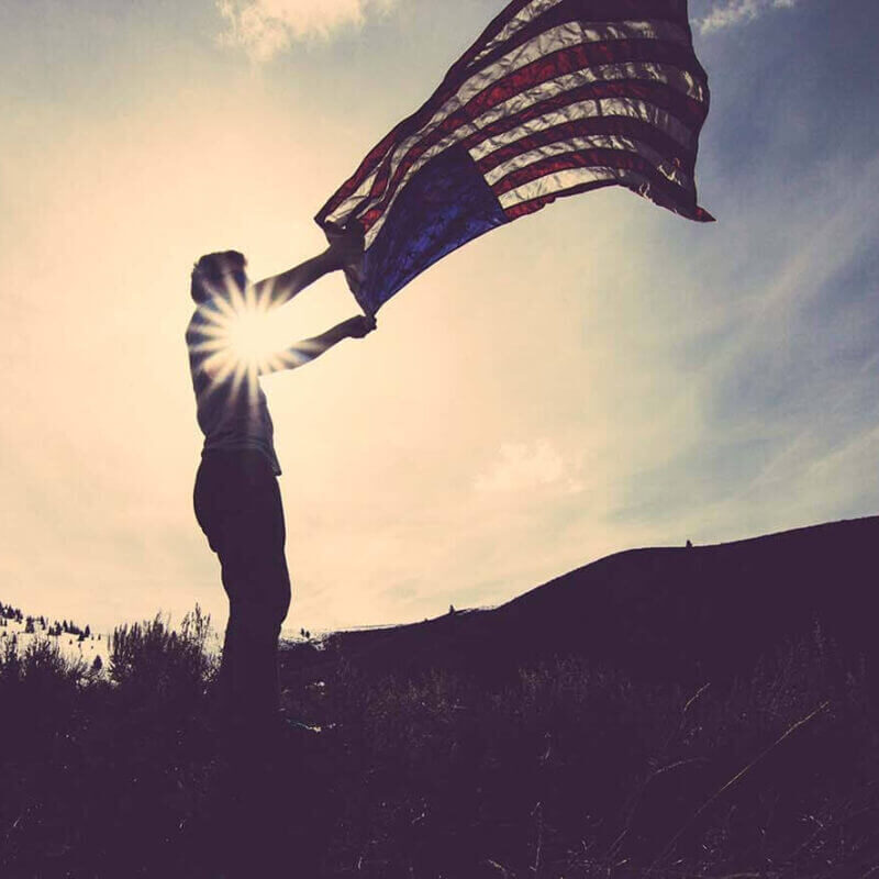 VA Pension Planning person holding American flag as it blows in the wind